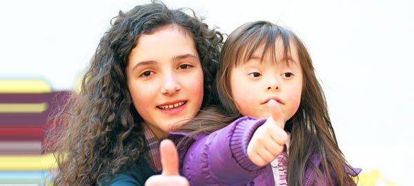 Picture of two girls with thumbs up, one with an intellectual disability